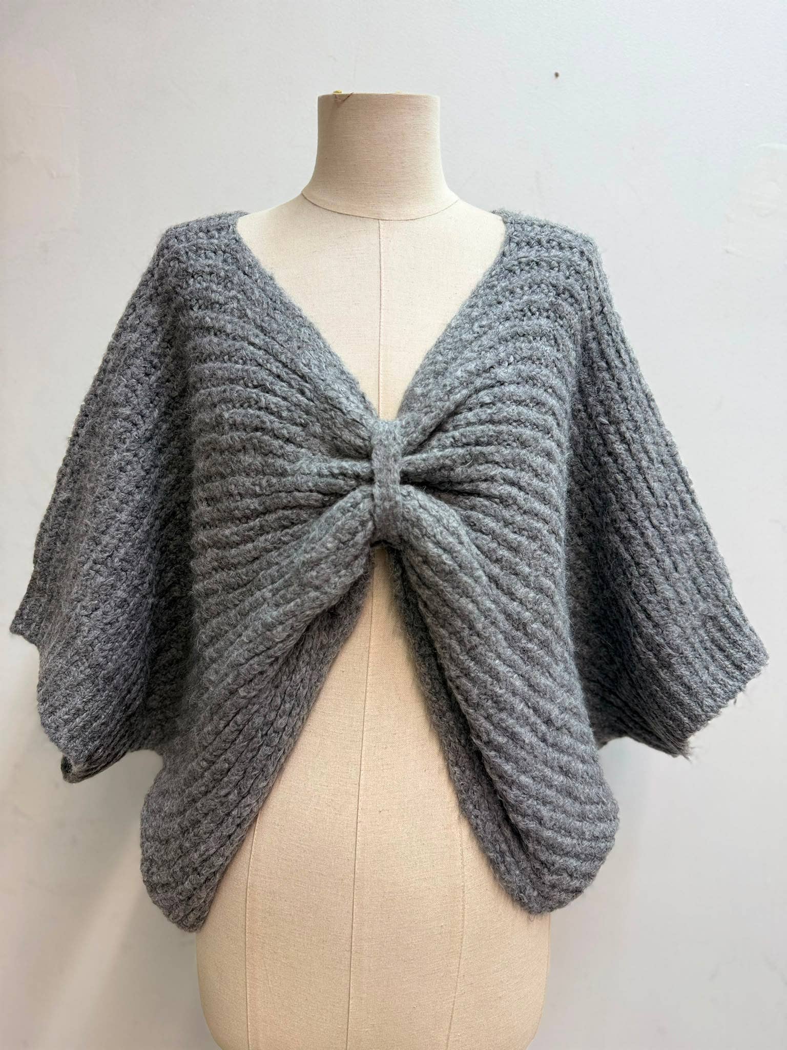Kurzes Strickgilet zum Binden in Grau – Detailansicht mit Raffungseffekt durch Bindeband