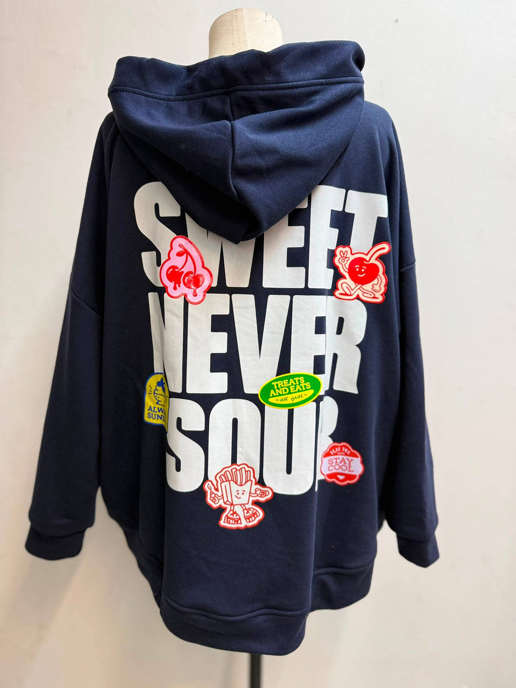Oversize Hoodie Sweet Never Sour in Marineblau – Rückenansicht auf Schneiderpuppe mit großem Print und bunten Cartoon-Patches