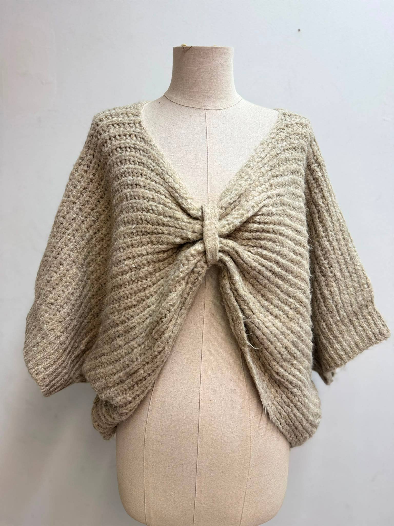 Kurzes Strickgilet zum Binden in Taupe – Detailansicht mit Raffungseffekt durch Bindeband