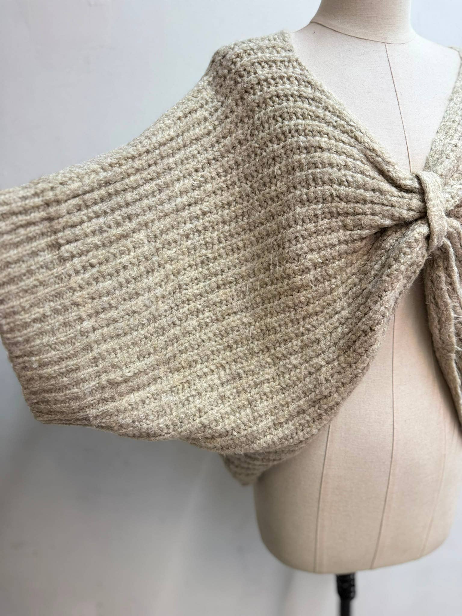Kurzes Strickgilet zum Binden in Taupe – Seitenansicht mit weitem Schnitt und V-Ausschnitt